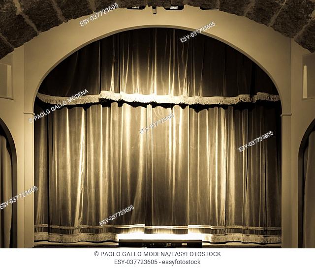 A red curtain in an old and very small Italian theatre