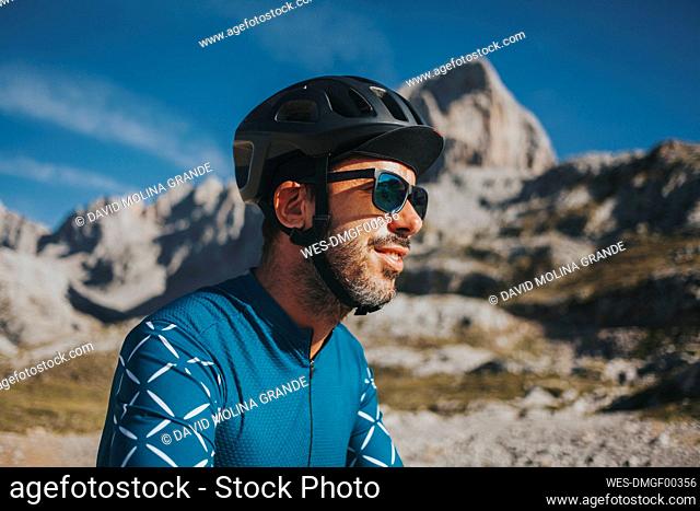 Cyclist wearing sunglasses and cycling helmet at Picos de Europa National Park on sunny day, Cantabria, Spain