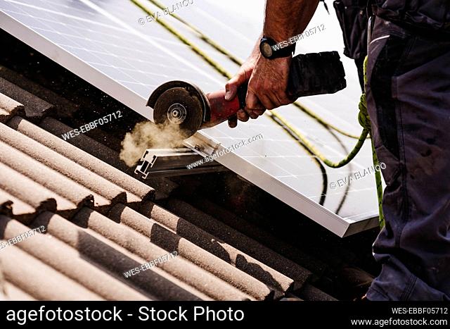 Electrician cutting metal using grinder on roof