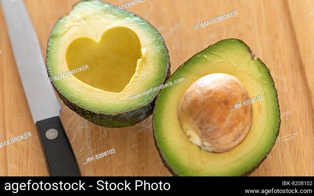 Fresh cut avocado with heart shaped pit area on wooden cutting board