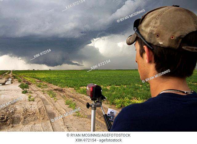 A storm chaser participating in Project Vortex 2 near Dodge City, Kansas, USA, June 9, 2009  A wall cloud is in the distance  Project Vortex 2 is a two year...