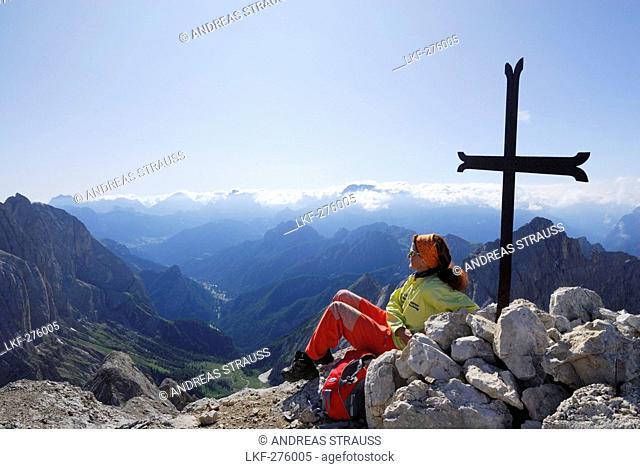 Woman enjoying view at summit cross of Cima Ombretta, Marmolada, Dolomites, Trentino-Alto Adige/South Tyrol, Italy