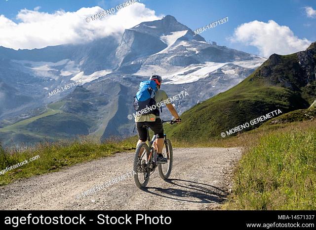 Austria, Tyrol, Alps of Tux. a man riding an e-bike (emtb) uphill to the Tuxerjoch, on the background the Hintertux glacier