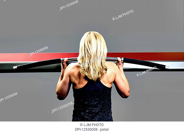 A middle-aged woman working out at a fitness facility doing chin-ups; Spruce Grove, Alberta, Canada