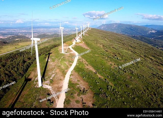 Aerial view of windmills farm for renewable energy production on beautiful blue sky. Wind power turbines generating clean renewable energy for sustainable...