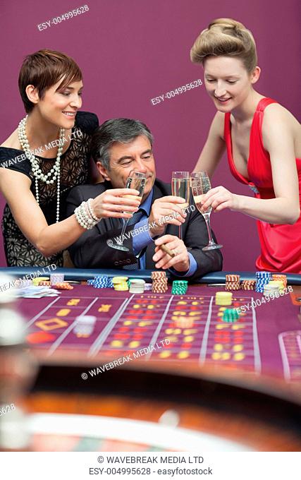 Women and man clinking glasses at the casino
