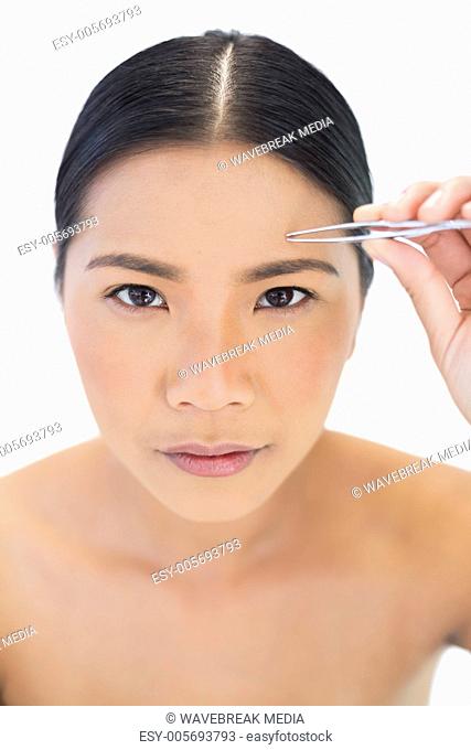 Natural model using tweezers for her eyebrow