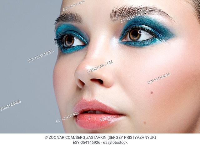 Closeup macro portrait of female face. Woman with evening beauty makeup. Girl with perfect skin and blue-green smoky eyes eye shadows