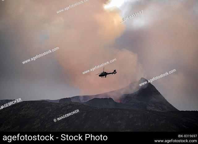 Helicopter flying over smoking active volcanic crater, glowing lava, volcanic eruption, active table volcano Fagradalsfjall, Krýsuvík volcanic system