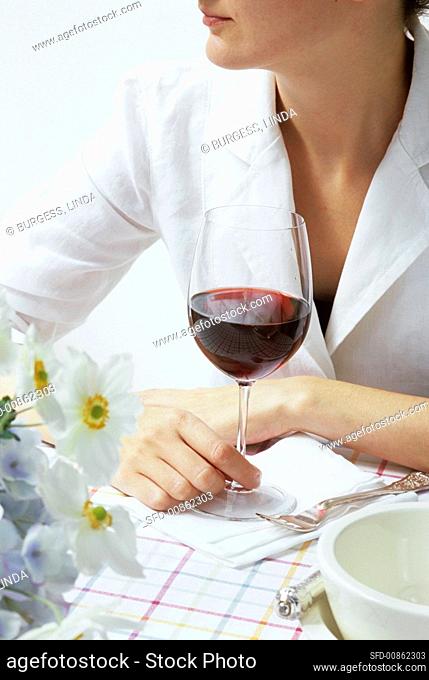 Young woman sitting at table with a glass of red wine