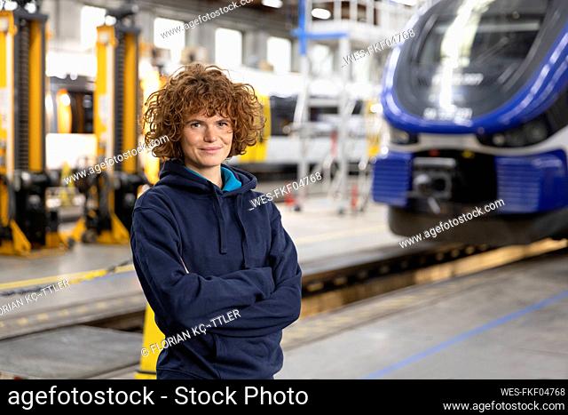 Confident engineer with arms crossed standing in warehouse at manufacturing industry