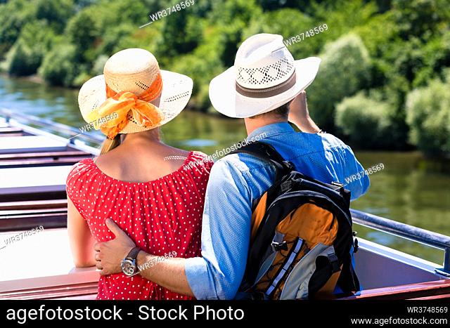 Happy couple on river cruise wearing sun hats in summer
