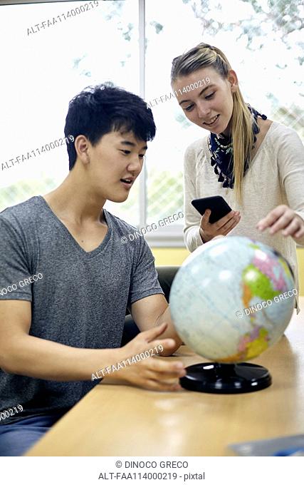 Students looking at globe in class