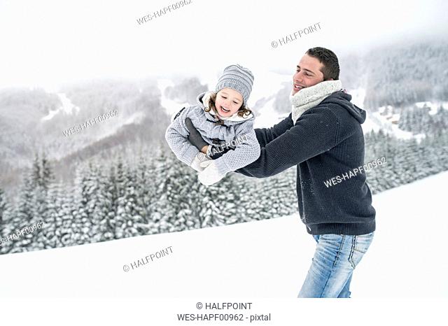 Father playing with daughter in winter landscape