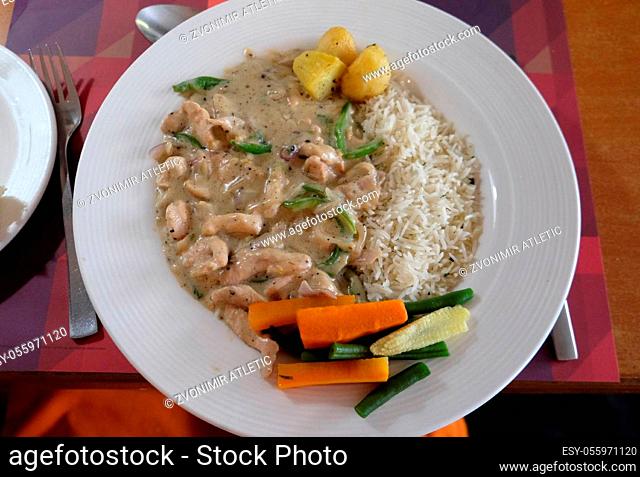 Chicken stroganoff with white rice and vegetables in One Step Up restaurant in Kolkata, West Bengal, India