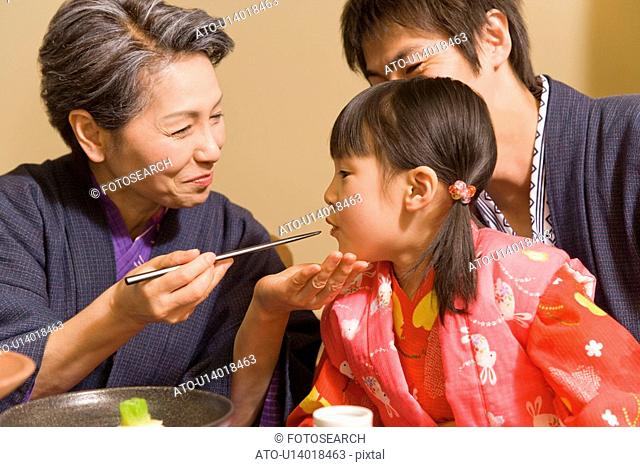 Senior woman feeding granddaughter, smiling