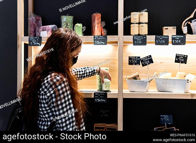 Woman wearing protective face mask choosing food displayed at store