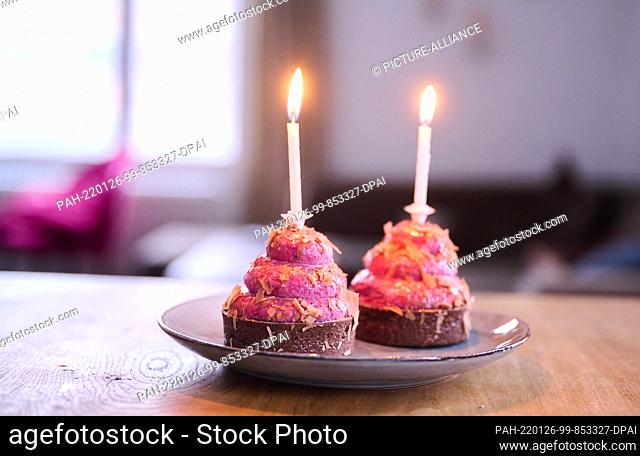 PRODUCTION - 12 January 2022, Berlin: ILLUSTRATION - Two cupcakes with burning candles are placed on a table. (posed scene) Photo: Annette Riedl/dpa