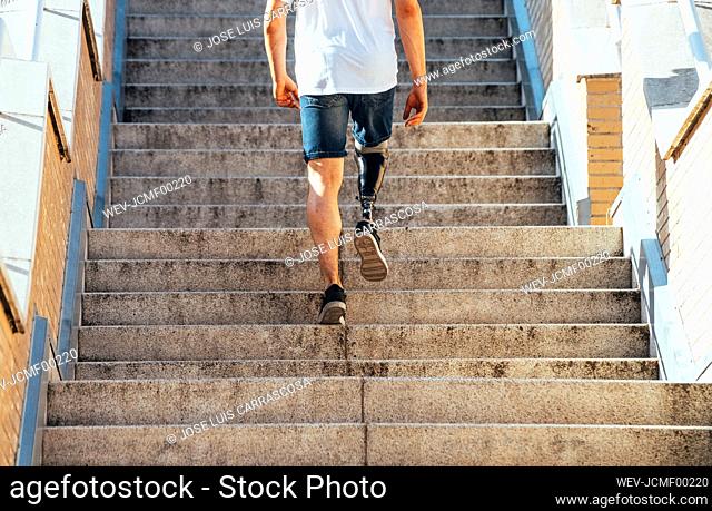 Young man with leg prosthesis walking upstairs