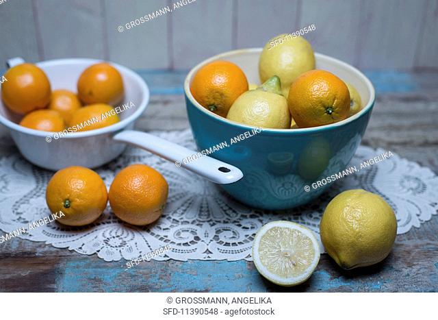 Oranges and lemons in a blue porcelain bowl and oranges in a white enamel colander