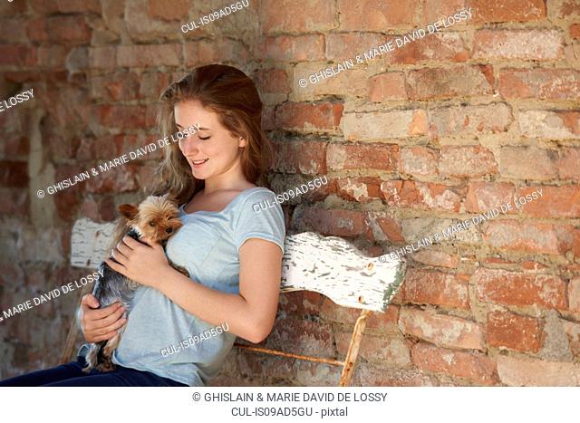 Teenage girl on bench with dog, smiling