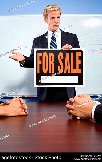 Businessman holding for sale sign