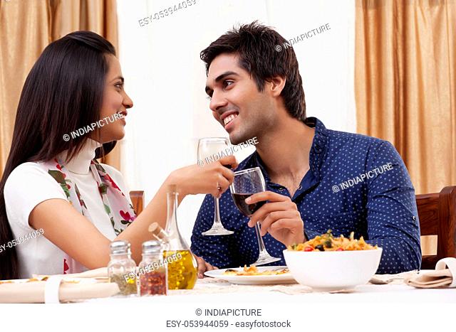 Couple looking at each other while clinking wine glass at restaurant