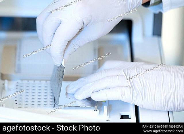10 October 2023, Saxony, Dresden: Benjamin Lange, service technician, inserts a PCR plate into a ""Modaplex"" diagnostic device in a laboratory of the...