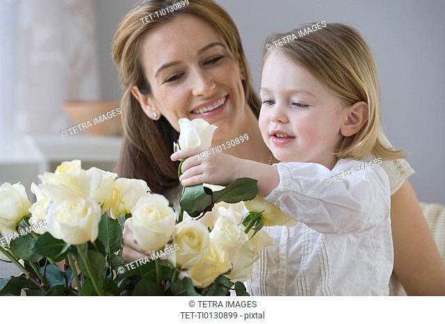 Mother watching daughter arrange flowers