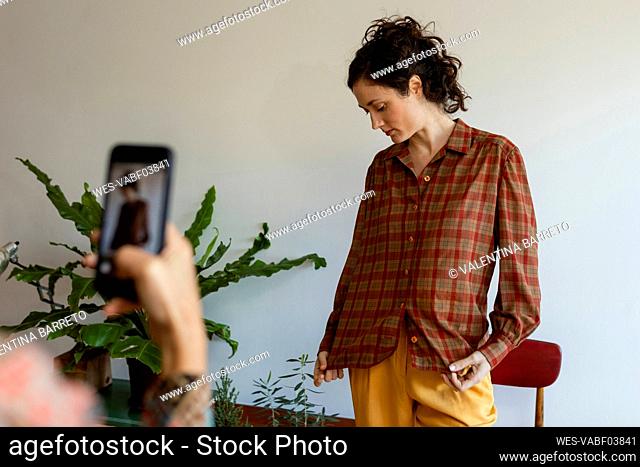 Woman taking photo of female model standing at home