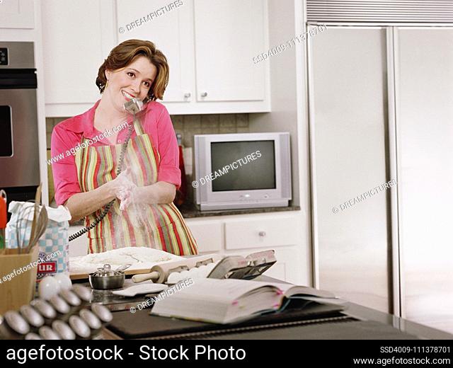 Young woman baking as she talks on the phone