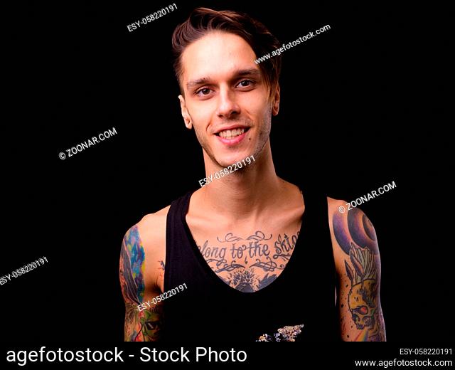 Studio shot of young handsome rebellious man against black background