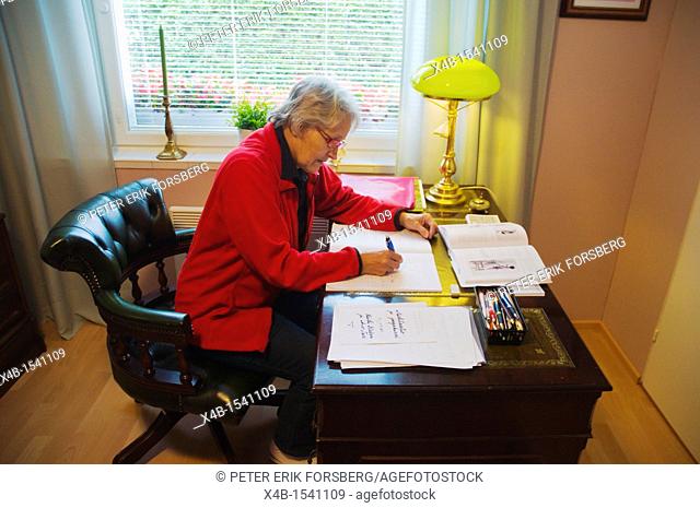 Woman in her early 70s doing paperwork Finland Europe