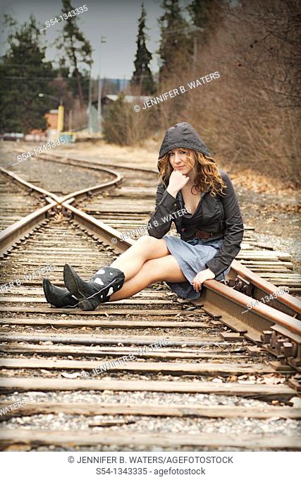 A young woman sitting on train tracks