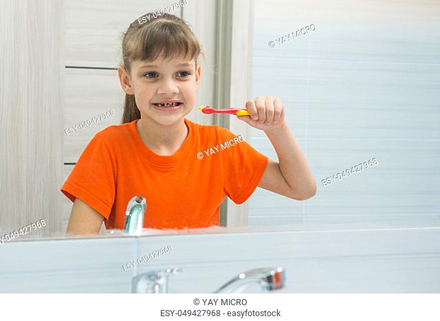 Seven-year-old girl looks at herself in the mirror before brushing her teeth