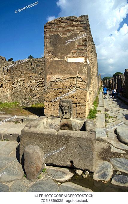 POMPEII, ITALY, July 2018, Tourist at stone water tank in one of the street