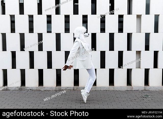 Woman wearing dog mask dancing on footpath