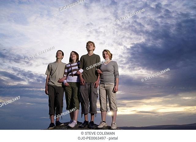 Teenage friends standing on rock viewing countryside