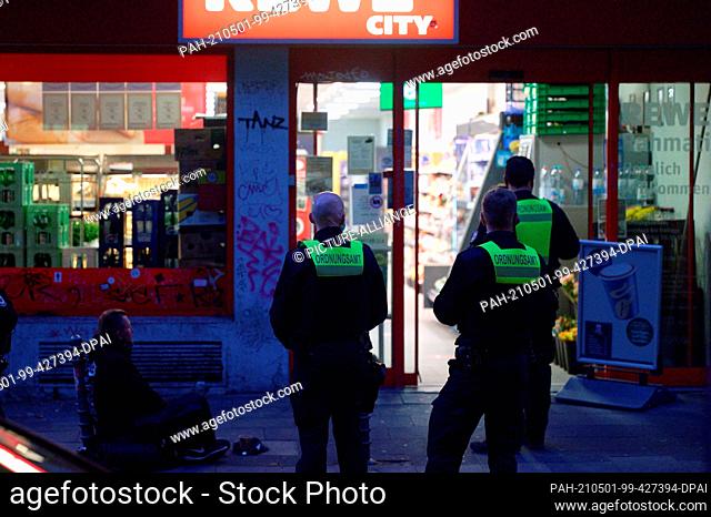 30 April 2021, North Rhine-Westphalia, Cologne: Employees of the public order office monitor the closing of a supermarket at the beginning of the curfew at...