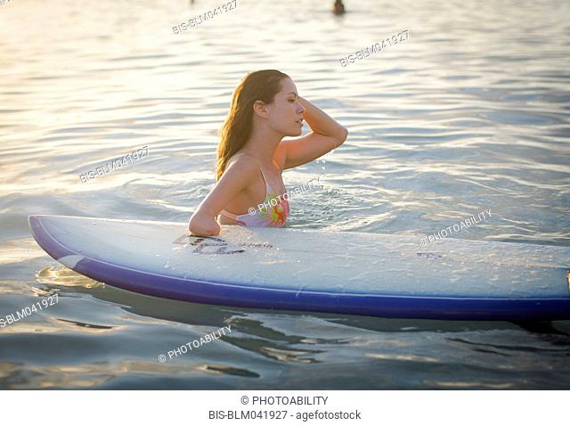 Amputado de raza mixta con tabla de surf en el océano