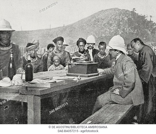 Albert Sarraut (1872-1962), French Governor of Indochina, at a table, shows how a phonograph works to the inhabitants of a Hmong hamlet, Laos