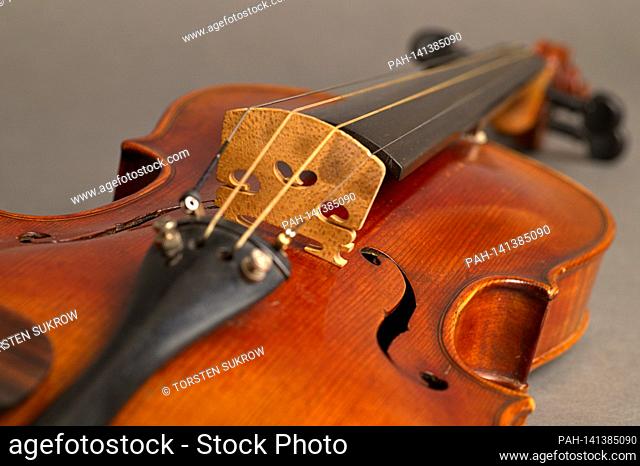 An old violin with slight scratches and damage in the bleed on a neutral, gray background. | usage worldwide. - /Deutschland