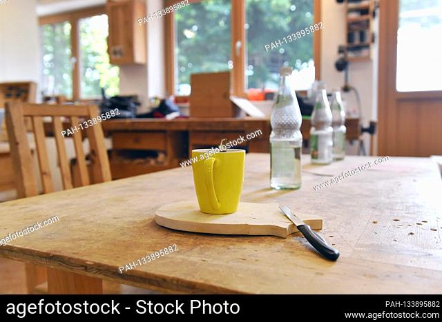 Topic picture: carpentry, craft. Lunch table, table with an empty cup and water bottles after the breakfast break in a carpenter's workshop on 07/15/2020