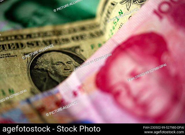 ILLUSTRATION - 27 April 2023, Berlin: A Chinese 100 yuan banknote (front) and a 1 US dollar bill (M) are lying on a table
