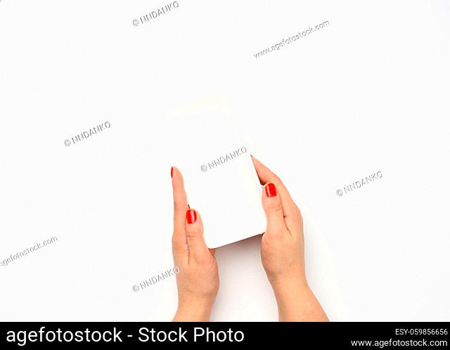 Female hands hold an empty rectangular disposable plastic container on a white background, top view