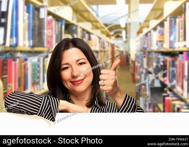 Pretty Hispanic Woman with Thumbs Up Leaning On White Board in the Library
