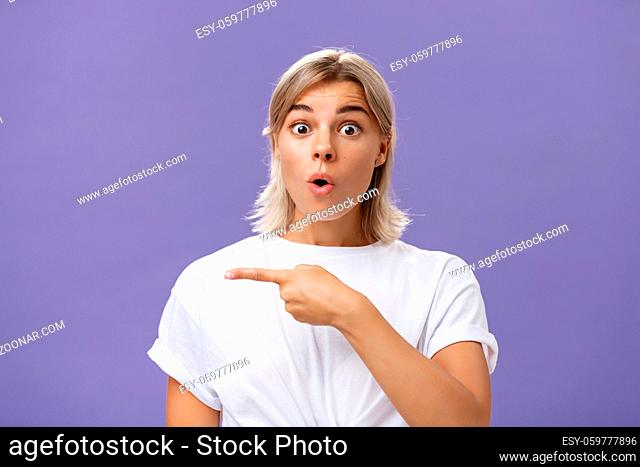 Waist-up shot of overwhelmed excited and surprised attractive urban female in white t-shirt folding lips gasping from amazement being questioned asking question...