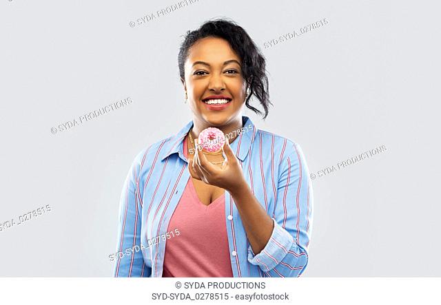 happy african american woman eating pink donut