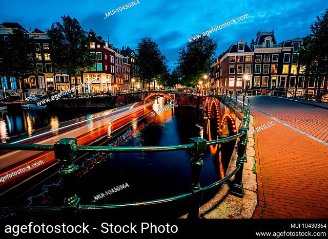 Evening in Amsterdam city, light trails and reflections on water at the Leidsegracht and Keizersgracht canals. Long exposure shot
