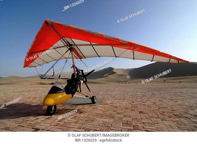 Microlight aircraft in front of the sand dunes of the Gobi Desert and Mount Mingshan near Dunhuang, Silk Road, Gansu, China, Asia